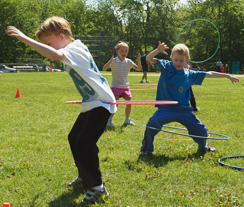 Juegos al aire libre, niños y salud. Niños en la playa. Jugando al Hula Hoop