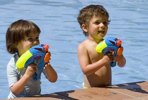 Juegos al aire libre, niños y salud. Niños en la playa. Niños con pistolas de agua