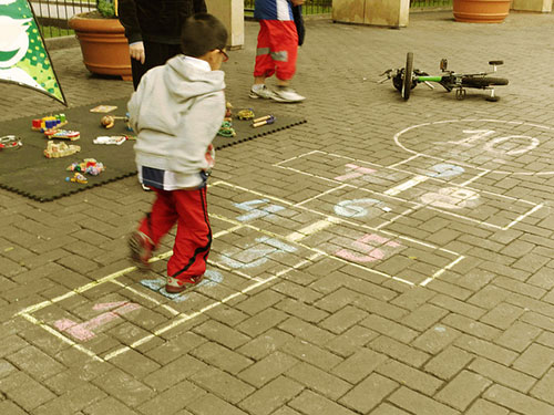 Juegos al aire libre, niños y salud. Niños en la playa. Rayuela o tejo